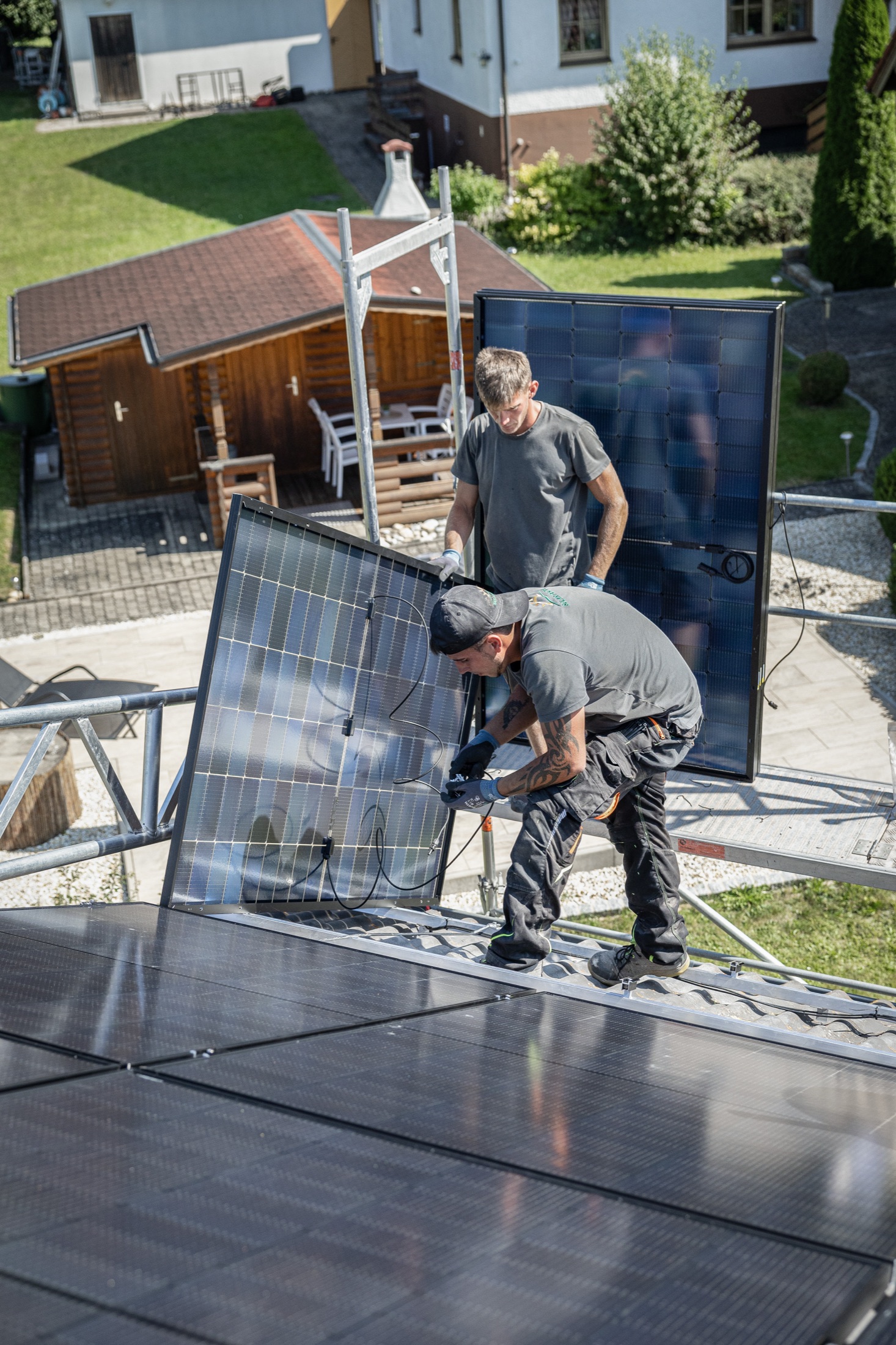 Monteure von Solartech verlegen schwarze Solarmodule auf einem Hausdach